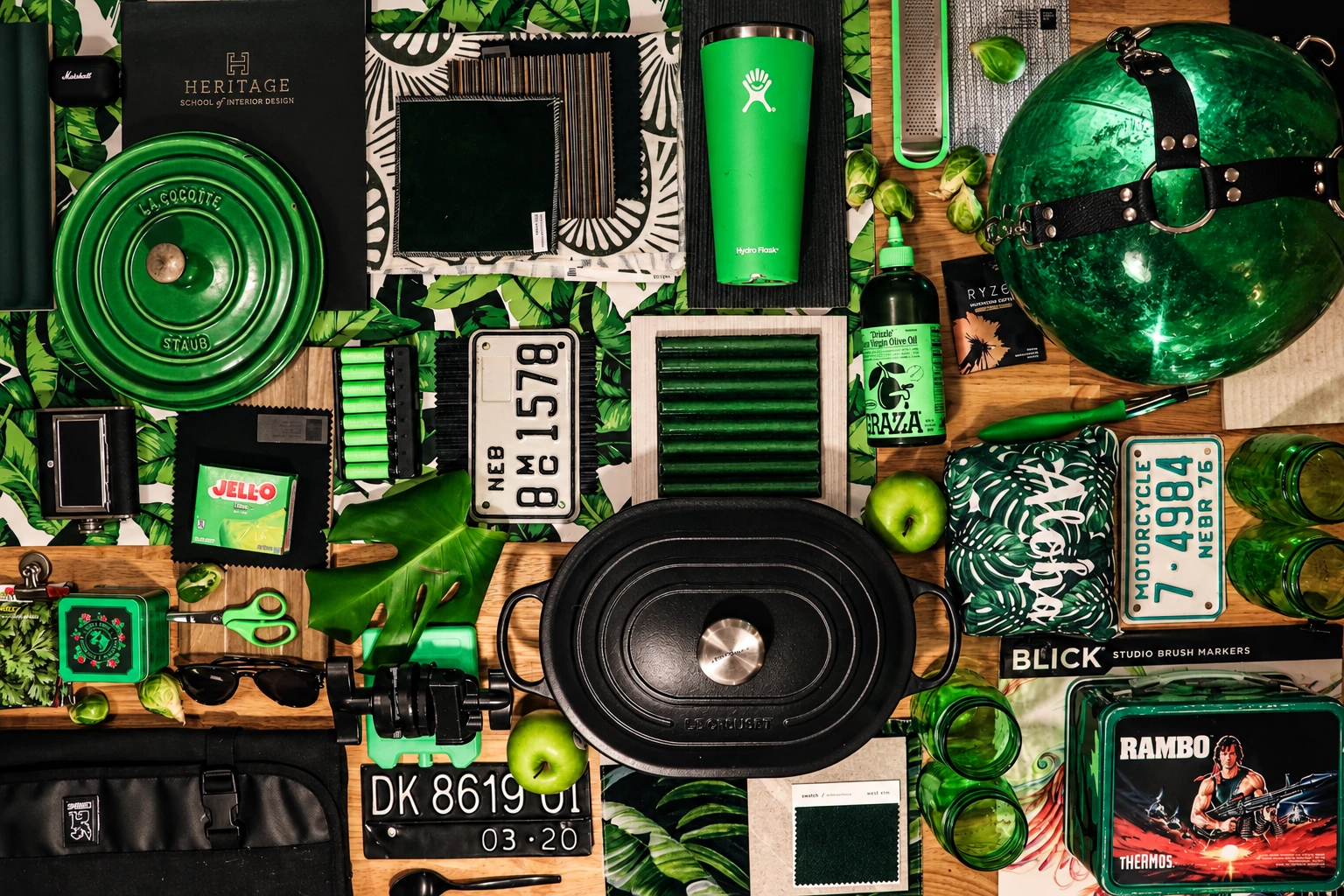 Green and black flat lay: cookware, travel objects, textiles, and design materials